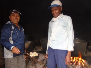 Noel og Charlotte er klare ved grytene for å koke ris og tilbehør (laouka). Det er mye røyk og det svir I øynene, men det går fint ler de begge.